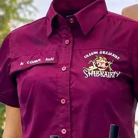 Camisa borgoña de manga corta con el logo del negocio bordado a color y el nombre del empleado