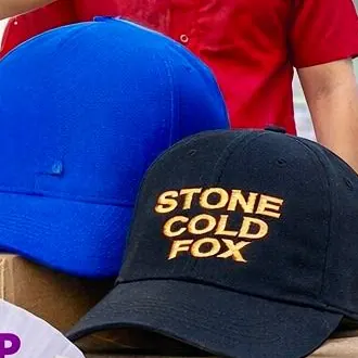 Gorra azul royal y gorra negra con el nombre de una marca bordado en dorado
