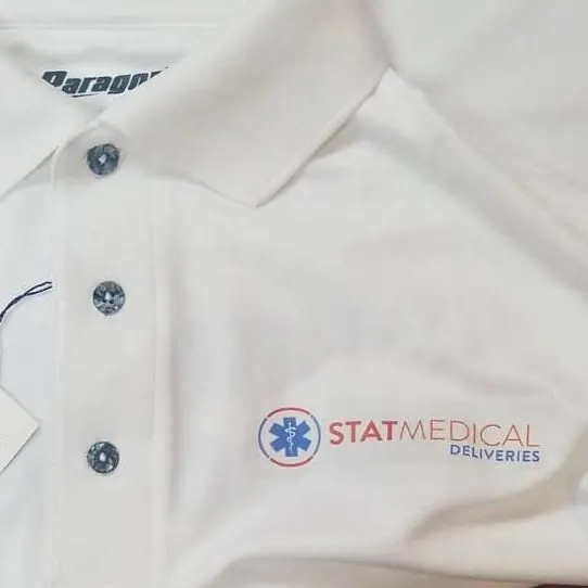 Polo blanco nuevo con etiqueta y el logo de una empresa de transporte médico bordado en el pecho